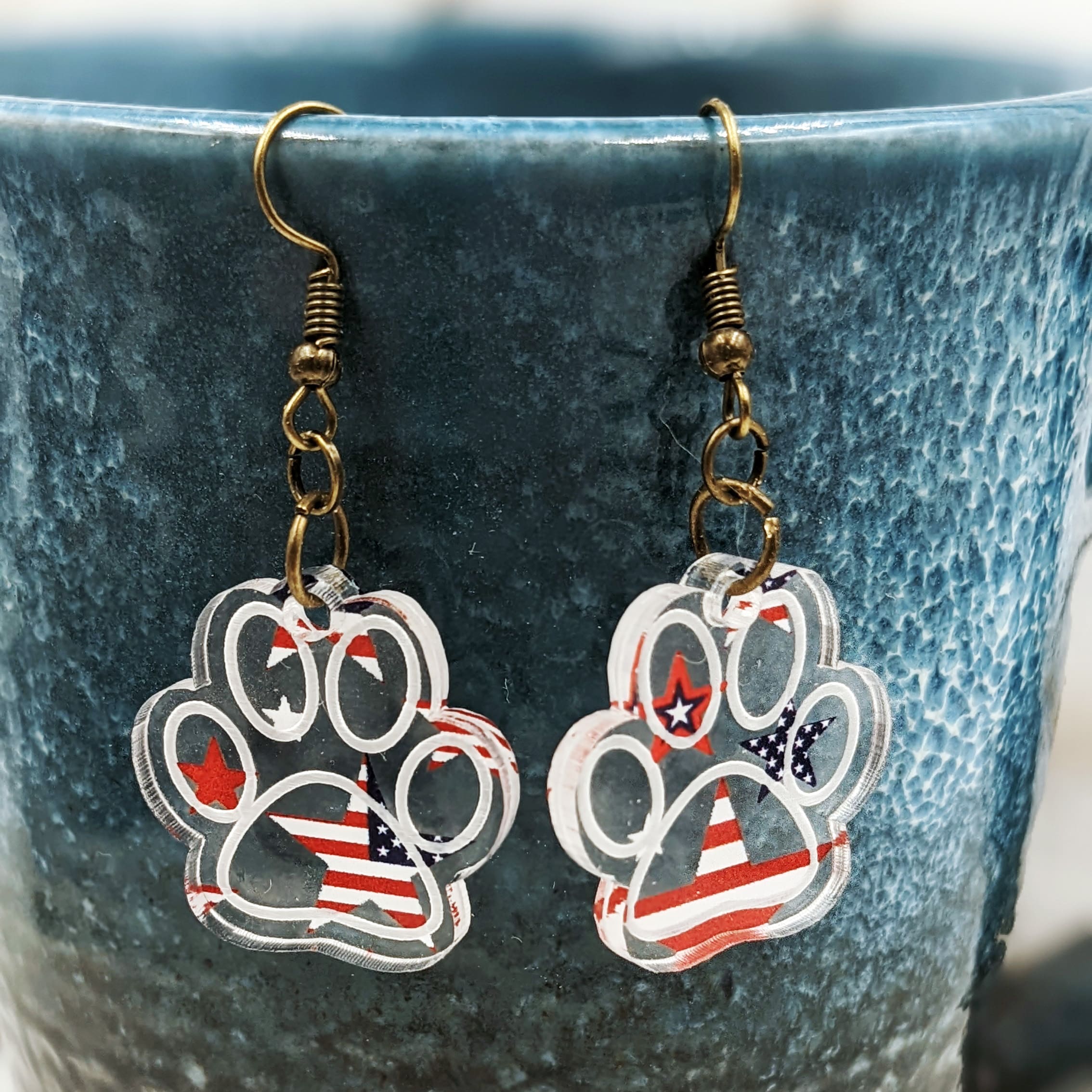 Acrylic patterned stars and stripes etched pawprint-shaped earrings.